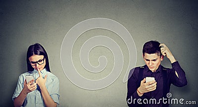 Perplexed man and woman looking at mobile phone Stock Photo