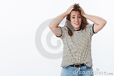 Perplexed worried bothered cute overweight young curly-haired girl mess-up hair hold hands head troubled assuming bad Stock Photo