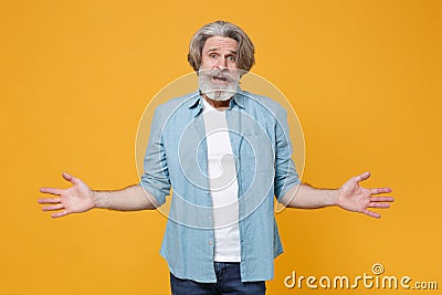 Perplexed worried elderly gray-haired mustache bearded man in casual blue shirt posing isolated on yellow background Stock Photo