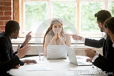 Perplexed young woman looking at coworkers pointing fingers at h Stock Photo