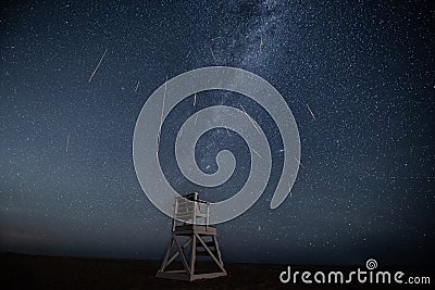 Perseid meteor shower and milky way above a chair on beach Stock Photo