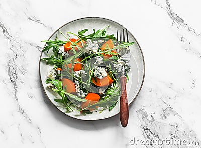 Persimmon, arugula, gorgonzola salad - vegetarian seasonal snack, appetizer on a light background, top view Stock Photo