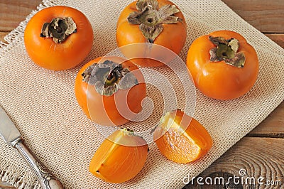 Persimmon whole and cut into pieces on canvas Stock Photo