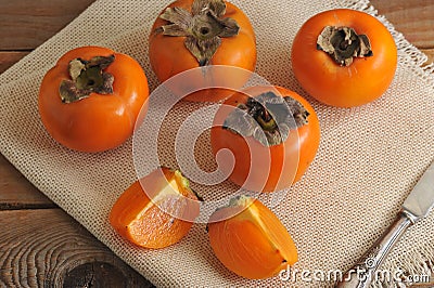 Persimmon whole and cut into pieces on canvas Stock Photo