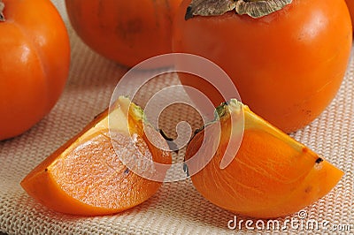 Persimmon whole and cut into pieces on canvas Stock Photo