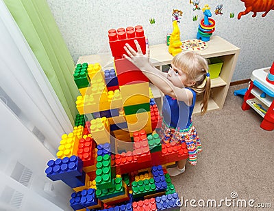 Persistent little girl building big block tower in daycare Stock Photo