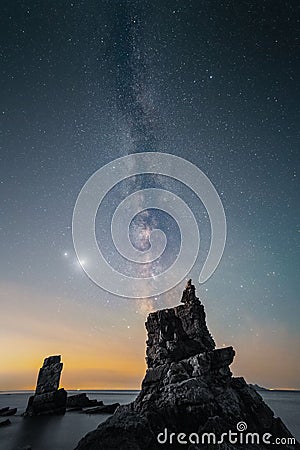 Person admires the tranquil beauty of the milky way galaxy sky from a cliff in Dalian, Liaoning Stock Photo