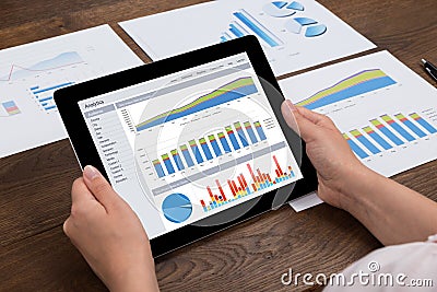 Person Analyzing Financial Statistics On Digital Tablet Stock Photo