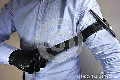 Person in black medical gloves Applies the tourniquet to his hand to prevent bleeding during the first aid. Trauma patient. Combat Stock Photo