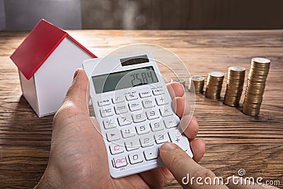 Person Calculating With House Model And Coin Stacked Stock Photo