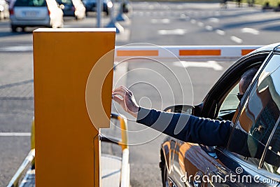 Person in the car inserting into or removing ticket from parking vending machine. Paying, entering parking lot or Editorial Stock Photo