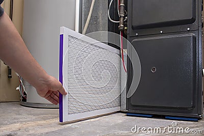 A person changing an clean air filter on a high efficiency furnace Stock Photo