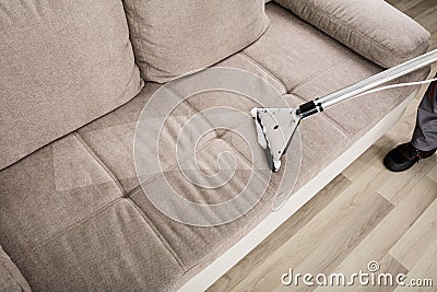 Person Cleaning Sofa With Vacuum Cleaner Stock Photo