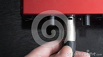 Person connecting a microphone cable to an audio interface Stock Photo