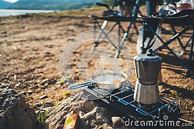 Person cooking fried eggs hot coffee in nature camping outdoor, cooker prepare scrambled omelette breakfast picnic, tourism Stock Photo