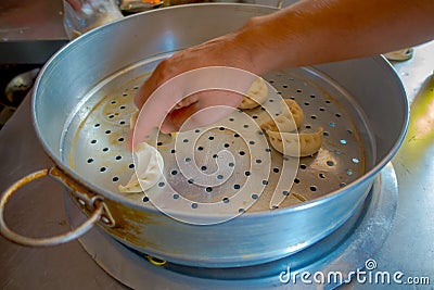 Person cooking a momo food over a metallic tray in the kitchen, type of South Asian dumpling native to Tibet, Nepal Stock Photo