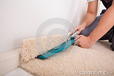 Person Cutting Carpet With Cutter Stock Photo