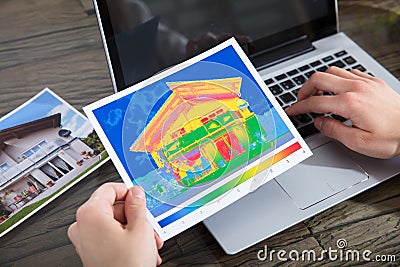 The Person Detecting Heat Loss Of A House Using Laptop Stock Photo