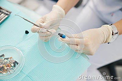 Person dipping dental instrument in dental composite filling bottle Stock Photo