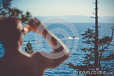 A person drinking cold beer and looking at the motorboat near the sea on a sunny day Stock Photo