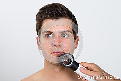 Person Examining Man Face With Dermatoscope Stock Photo