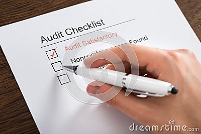 Person Filling Audit Checklist Form At Desk Stock Photo