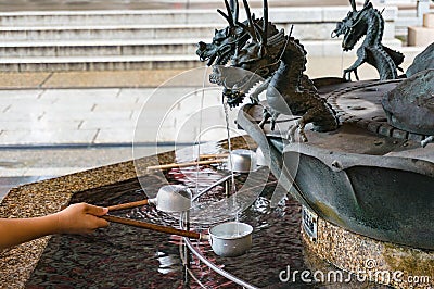 Person filling up ladle with water of chozuya fountain Stock Photo