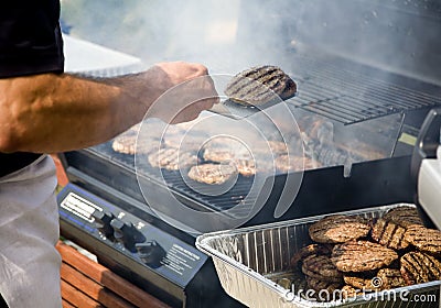 Person Flipping Burgers During BBQ Stock Photo