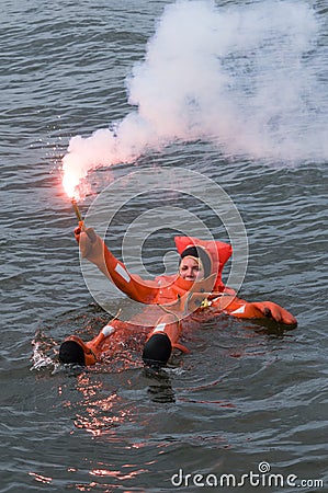 Person floating in survival suit holding red handflare Editorial Stock Photo