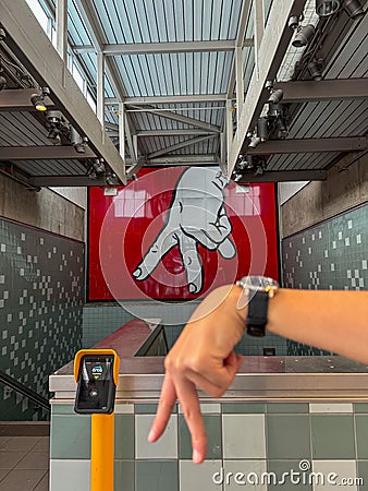 Person gesturing towards a round clock face mounted on a white-tiled subway wall Stock Photo