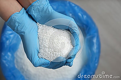 Person in gloves holding pile of ammonium nitrate pellets over bag, top view. Mineral fertilizer Stock Photo