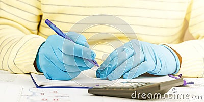 Person in gloves writes in notebook at outdated calculator Stock Photo