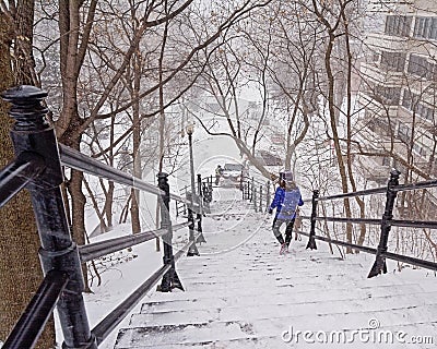 PErson going down on the stairs from Mont Royal, Montreal, in the snow Editorial Stock Photo