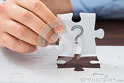 Person hand holding puzzle with question mark Stock Photo