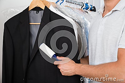 Person hand removing dust with lint roller Stock Photo