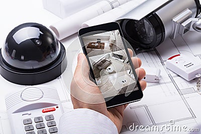 Person Hand Using Home Security System On Mobilephone Stock Photo