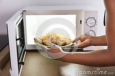 Person Heating Fried Food In Microwave Oven Stock Photo