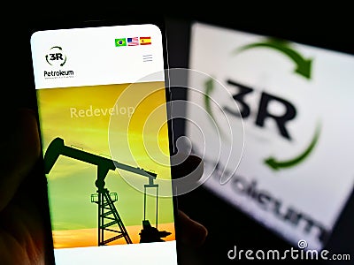 Person holding cellphone with web page of Brazilian oil and gas company 3R Petroleum SA on screen in front of logo. Editorial Stock Photo