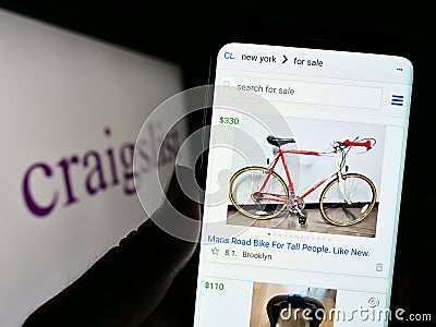 Person holding cellphone with webpage of classified advertisements company Craigslist Inc. on screen with logo. Editorial Stock Photo