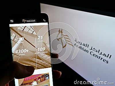 Person holding cellphone with webpage of shopping mall operator Arabian Centers Company on screen in front of logo. Editorial Stock Photo