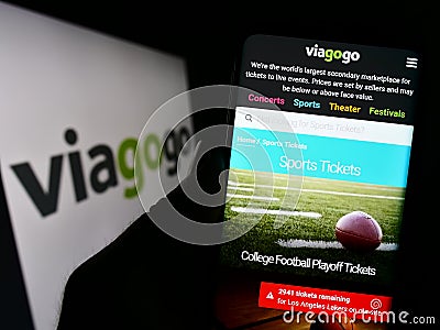 Person holding cellphone with webpage of US ticket exchange platform company Viagogo on screen in front of logo. Editorial Stock Photo