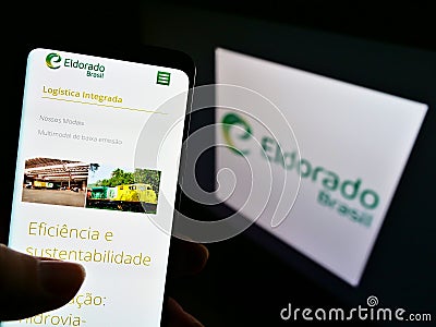 Person holding cellphone with website of Brazilian pulp manufacturer Eldorado Brasil Celulose on screen with logo. Editorial Stock Photo