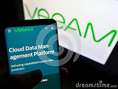 Person holding cellphone with website of Swiss IT company Veeam Software Group GmbH on screen in front of logo. Editorial Stock Photo