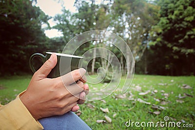Closeup of woman sitting relax on park, hands holding cup of tea or coffee. Stock Photo