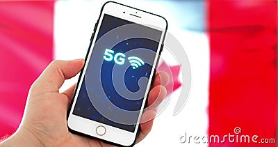 A person holding a iPhone with a 5G sign on a out of focus Canadian flag background. Calgary, Alberta, Canada. May 27, 2020. A person holding a iPhone with a 5G stock footage A person holding a iPhone with a 5G sign on a out of focus Canadian flag background. Calgary, Alberta, Canada. May 27, 2020. A person holding a iPhone with a 5G stock footage