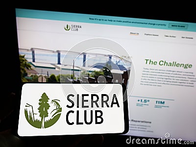 Person holding mobile phone with logo of American environmental organization Sierra Club on screen in front of web page. Editorial Stock Photo