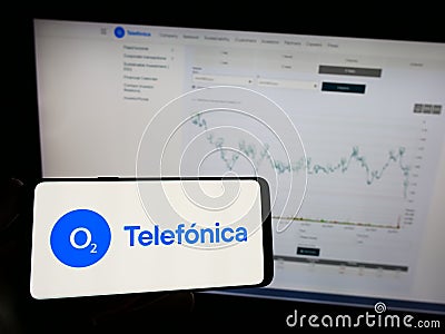 Person holding mobile phone with logo of company Telefonica Deutschland Holding AG on screen in front of web page. Editorial Stock Photo