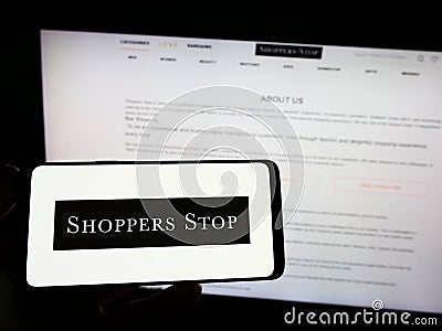 Person holding mobile phone with logo of Indian retail company Shoppers Stop Limited on screen in front of web page. Editorial Stock Photo
