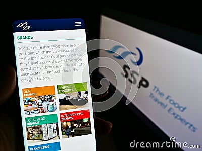 Person holding mobile phone with web page of British foodservice company SSP Group plc on screen in front of logo. Editorial Stock Photo