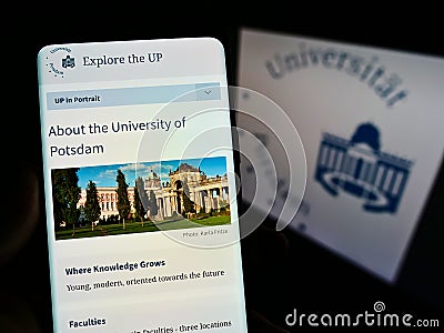 Person holding mobile phone with webpage of German university UniversitÃ¤t Potsdam on screen in front of logo. Editorial Stock Photo